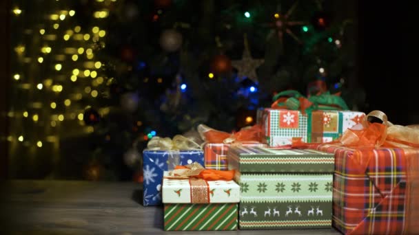 Hermosos regalos de Navidad en una mesa en casa y árbol con luces en el fondo, festividad y concepto de vacaciones — Vídeo de stock