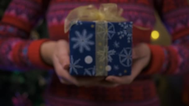 Mãos femininas dando um presente em papel de embrulho azul. Feliz Natal ou Feliz Ano Novo. Pessoa segurando a caixa para o Natal — Vídeo de Stock