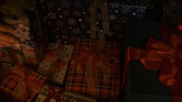 Το γυναικείο χέρι βάζει δώρο κάτω από το χριστουγεννιάτικο δέντρο. Όμορφα δώρα κάτω από το χριστουγεννιάτικο δέντρο. Το εσωτερικό της Πρωτοχρονιάς. Χριστουγεννιάτικο δέντρο, καλές γιορτές. Το κουτί δώρων της Πρωτοχρονιάς. Πνεύμα Χριστουγέννων, γιορτές, γιορτές — Αρχείο Βίντεο
