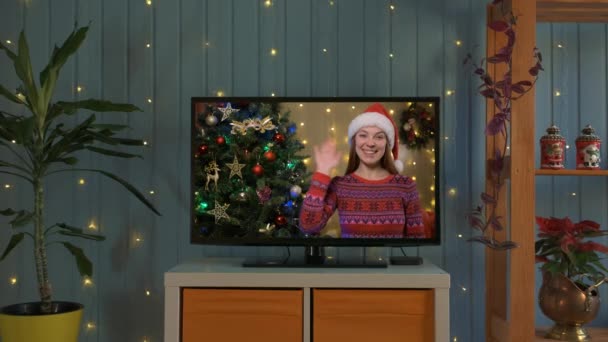 Uśmiechnięta kobieta w kapeluszu Mikołaja na teledysku, jest szczęśliwa i życzy Wesołych Świąt online — Wideo stockowe