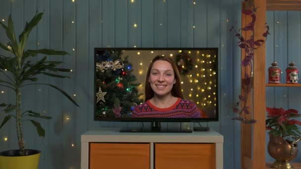 Glimlachende vrouw met kerstman hoed op een videocall, ze is gelukkig en wensen een vrolijk kerstfeest online — Stockvideo