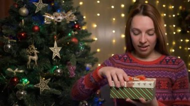 Mutlu Noeller ve mutlu yıllar konsepti. Kadın hediyeyi açar ve içinde ne olduğuna bakar.