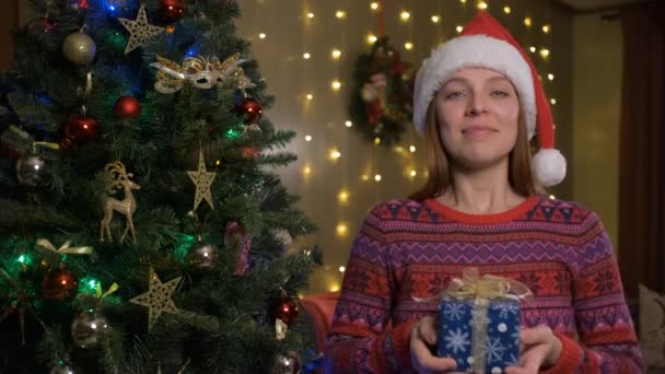 Jovem com chapéu de Papai Noel dando um presente certificado de presente. — Vídeo de Stock