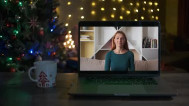 Genç bir kadın el sallıyor ve bir video çağrısında gülümsüyor. Noel zamanı. Yeni Yıl