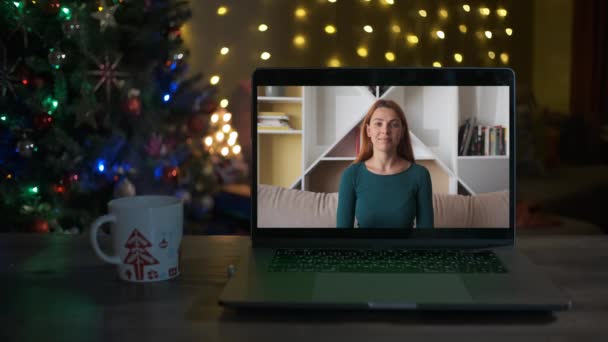 Una giovane donna saluta Ciao e sorride in un videocall. E 'Natale. Anno nuovo — Video Stock
