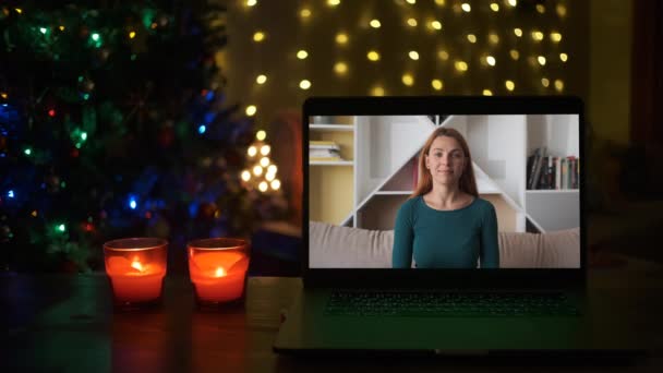 Una mujer joven saluda Hola y sonríe en un videocall. En Navidad. Año Nuevo — Vídeos de Stock