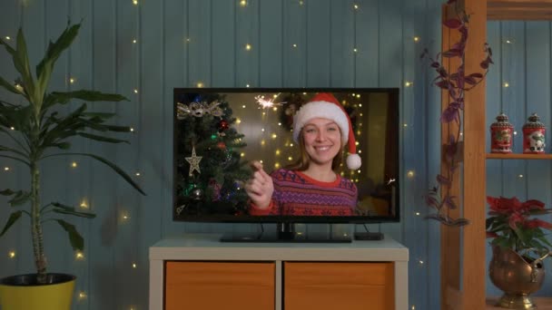 Donna felice con scintille e cappello da Babbo Natale si congratula con i parenti per il Natale tramite smart tv online. — Video Stock