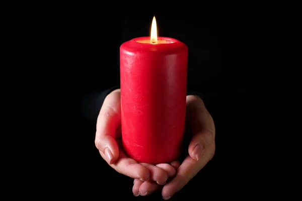 Red burning candle in a woman hand religion concept