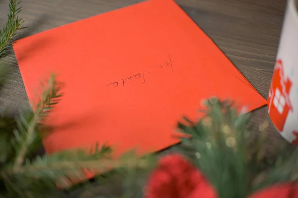 Ahşap bir masanın üzerinde Noel süsleri olan kırmızı bir zarf. Yüksek kalite fotoğraf