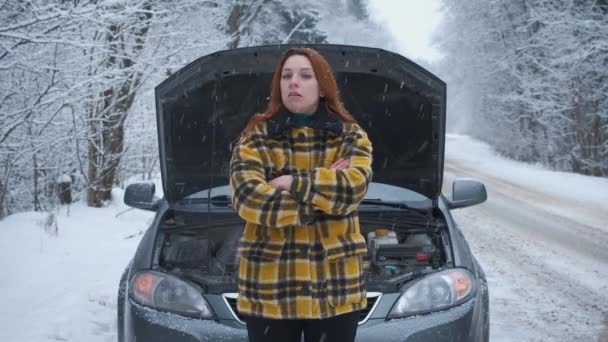 Une jeune femme dans la forêt d'hiver est debout sur la route avec une voiture cassée — Video