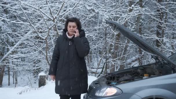Sorglig kvinna står nära den trasiga bilen och ringer — Stockvideo