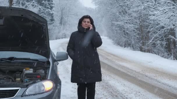 Uma mulher chama em seu smartphone enquanto está de pé por carro quebrado. — Vídeo de Stock
