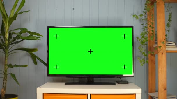 有绿色屏幕的电视合成。电视或电视-绿色屏幕-桌子上的房间.现代客厅里带铁轨绿屏的液晶电视 — 图库视频影像