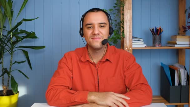 Jongeman in headset met microfoon die online een gesprek voert, op afstand studeert of projecten bespreekt met collega 's. — Stockvideo