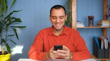 Genç adam elinde modern akıllı telefondan mesaj tutuyor..