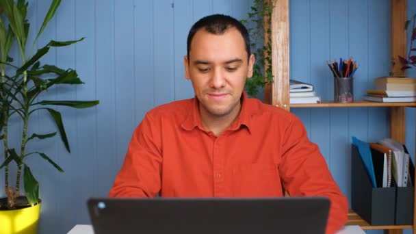 Egy fiatalember otthonról dolgozik a noteszben, kényelmes szobában.. — Stock videók