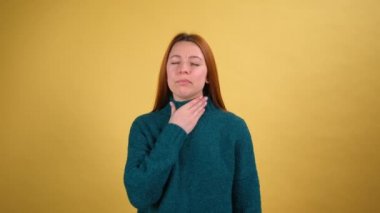 Boğazı ağrıyan genç bir kadın, solunum zorluğu çeken boyun, gırtlak iltihabı olan solunum enfeksiyonu, grip belirtileri, bademcik iltihabı ya da tiroid bozuklukları. Çekim sarı arkaplanda izole edildi