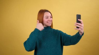 Neşeli genç bir kadın cep telefonuyla konuşuyor. Video görüşmesi yapıyor.