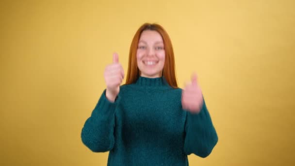 Hej ty. Jsem rád, že šťastná dívka s rudými vlasy ve svetru se vzrušeně usmívá a ukazuje na kameru, krása vybírá šťastný vítěz, ukazující na úžasné vás. vnitřní studio záběr izolované na žlutém pozadí — Stock video