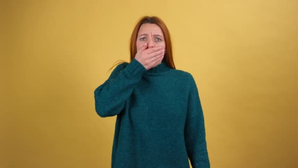 Frightened young woman closing her mouth with hand and looking intimidated scared at camera, gestures no. Shot isolated on yellow background — Stock Video