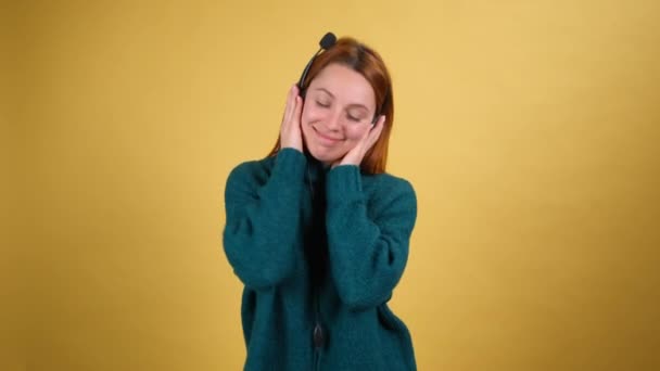 Vivid young woman listen music in headphones and dancing fooling around have fun gesticulating hands isolated on bright orange background in studio. People lifestyle concept. — Stock Video