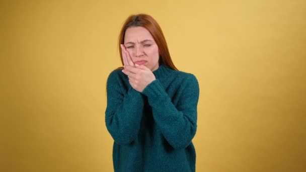歯の問題だ。痛みの頬に触れる不健康な若い女性,ひどい歯痛を患っています,虫歯や歯茎疾患から恐ろしい痛み.黄色の背景に隔離された室内 — ストック動画