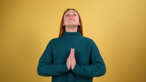 Avslapning, stresshåndtering. Ung kvinne som mediterer med hendene i været, gjør namaste, mudra gesture, konsentrerer sinnet føler harmoni. Innendørs isolert på gul bakgrunn – stockvideo