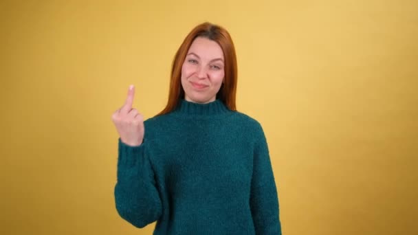 Zpátky. Nespokojená mladá žena ukazující prostředníček kameře, vyjadřující neúctu a negativitu vůči nenávistníkům, gesto protestu. Izolováno na žlutém pozadí — Stock video