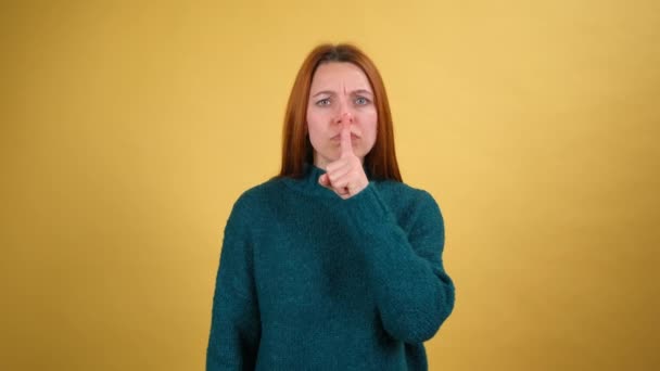 Be quiet. Young woman hushing with finger on lips gesture, asking to keep silence and looking at camera with angry serious expression. Indoor studio shot isolated on yellow background — Stock Video