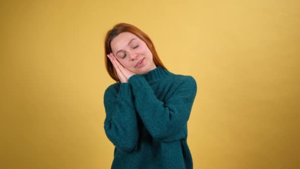 Linda mulher bonita dormindo nas palmas das mãos e sorrindo com expressão de prazer, sonhando confortável, dormindo a sesta durante o dia. interior isolado no fundo amarelo — Vídeo de Stock