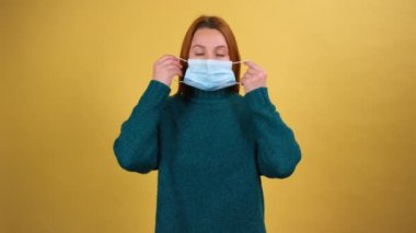 Solunum enfeksiyonunu önlemek için yüz hijyenik maskesi takan genç bir kadın. Grip olarak hava salgını, bulaşıcı koronavirüs. Sarı arka planda izole edilmiş kapalı stüdyo çekimi