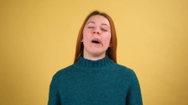 Sarı arka plan stüdyosunda izole edilmiş yorgun ve neşeli genç bir kadın. İnsanların yaşam tarzı konsepti. Elini başının üstüne koy, bir fincan kahve ya da çay iç.