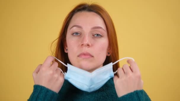 La giovane donna toglie la maschera medica per respirare aria fresca. studio al coperto girato isolato su sfondo giallo — Video Stock