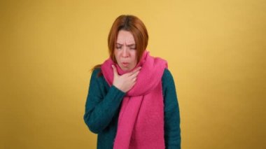 Sıcak eşarp takan, mendil içinde hapşıran, mevsimsel alerji ya da grip belirtileri gösteren, grip, viral enfeksiyon kapmış, burun akıntısı olan genç bir kadın. Stüdyo çekimi sarı arkaplanda izole edildi