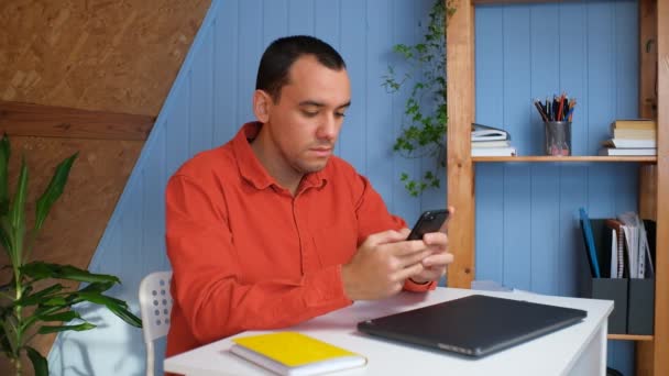 Młody człowiek trzymający nowoczesną wiadomość SMS-ową w biurze. Młody biznesmen wykorzystujący pomocne aplikacje mobilne do organizacji zarządzania czasem pracy — Wideo stockowe