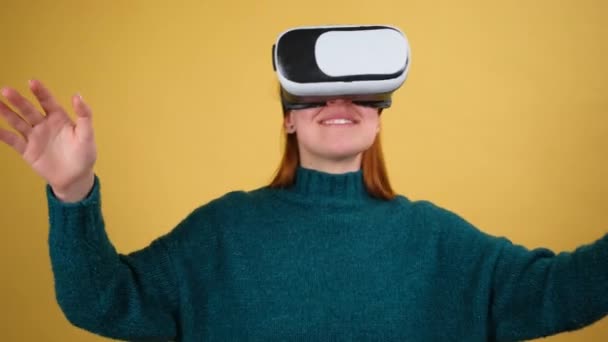 Úžasná mladá žena pomocí helmy VR aplikace sluchátka hrát simulační hru, kreslení. Sledování virtuální reality 3D 360 videa. Izolováno na žlutém pozadí ve studiu. — Stock video