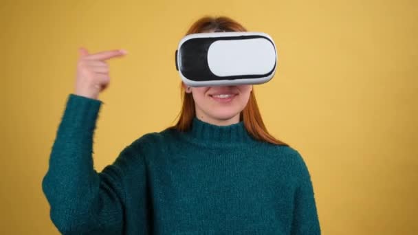 Молода жінка використовує шолом для гарнітури VR-додатків. Ізольовані на жовтому тлі в студії — стокове відео