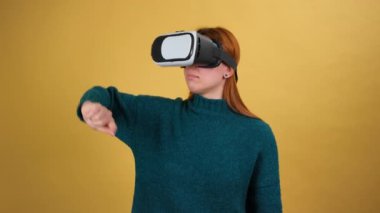 VR uygulaması kulaklık kullanan genç bir kadın. Jestler kayıyor. Sanal gerçeklik 3D 360 videosunu izliyorum. Stüdyoda sarı arka planda izole edilmiş.