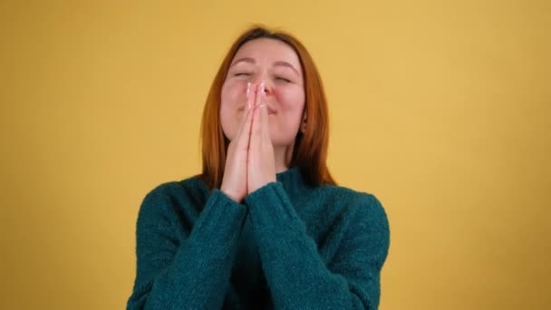 Upset young woman appealing to heaven with pleading imploring eyes, keeping prayer gesture and asking help. Please god, Im begging. indoor isolated on yellow background — Stock Video