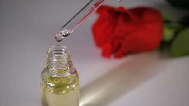 Cosmetic oil for face and body, bottle with oil on rose in the background, place for text — Stock Video