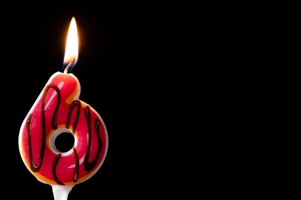 在黑色背景下庆祝六号生日的甜甜圈蜡烛 图库图片