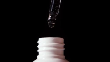 Pipetten dökülen serum damlalarının yakın çekimi. Organik özü. Cilt bakımı ve alternatif tıp. Tıbbi yağ. Yavaş Hareket