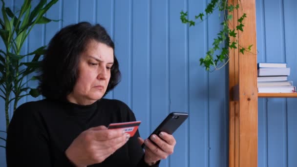 Oude vrouw online winkelen thuis op de smartphone, het typen van credit card nummer en annuleer de aankoop. Concept Fout debiteren van geld of Er staat geen geld op de kaart of het stelen van geld van de kaart. — Stockvideo