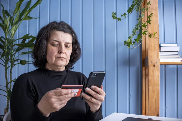 Kredi kartı ve akıllı telefon taşıyan yaşlı bir bayan. İnternetten alışveriş yapan mutlu bayan alışverişçi kolay taşınabilir ödemeler yapıyor. E-bankacılık uygulama servisi. Yaşlılar ve modern teknoloji kavramı