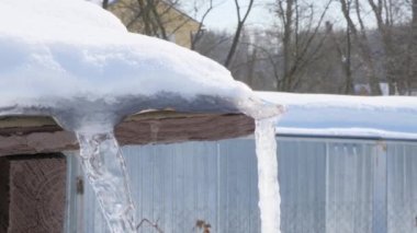 Güneşli bir kış gününde bir ahşap evin çatısından sarkan buz saçakları eriyip güneşe damlıyor. Isınıyor. Buz saçaklarının üzerinde bahar güneşi parlıyor. Su hızla damlıyor.