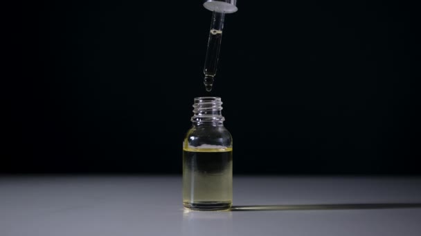 Bottle with serum and pipette on black background close-up. — Stock Video