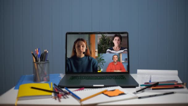 Uma jovem está falando em uma videochamada com um jovem e uma mulher. Uma jovem ensina online — Vídeo de Stock