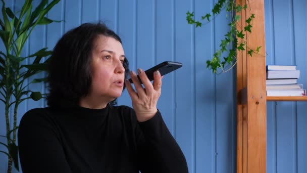 Orta yaşlı kadın telefonda konuş evde sanal dijital ses tanıma asistanı, kıdemli bayan komuta yardım mesajı, mobil ai teknolojisi konsepti etkinleştir — Stok video