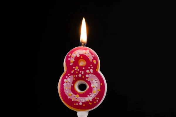 Torta de cumpleaños número 8 velas rosadas de rosquilla encendidas por un fondo más claro y negro —  Fotos de Stock
