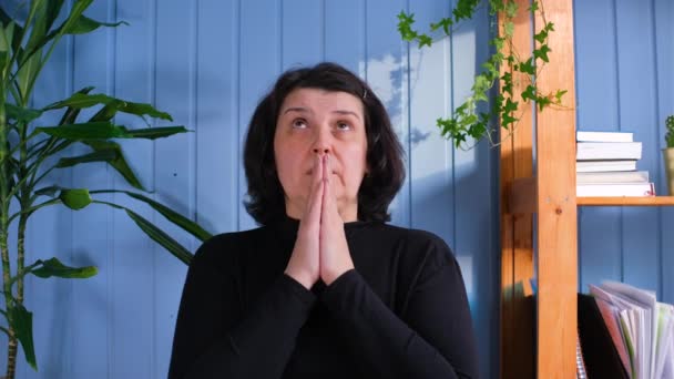 Frau mittleren Alters betet zu Hause — Stockvideo